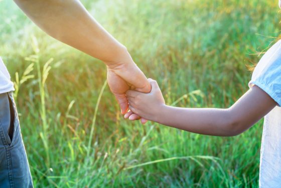 a parent who called a family law attorney troy holds the hand of a small child