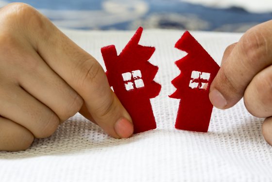 divorce concept for a wayne county divorce lawyer of a little red house being split in half by hands